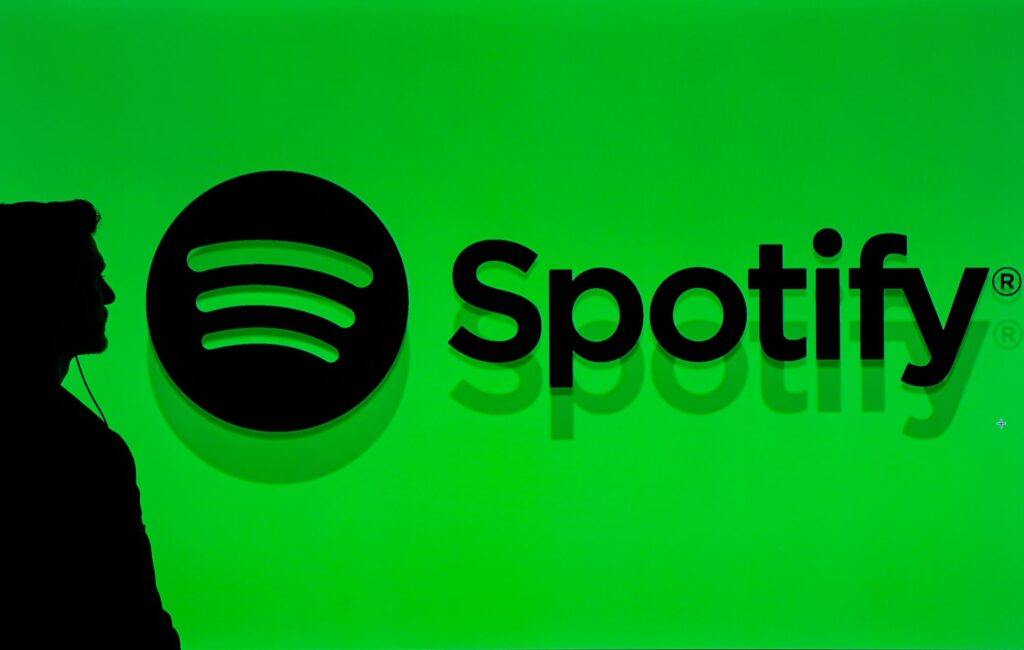 A man passing through a screen displaying Spotify logo